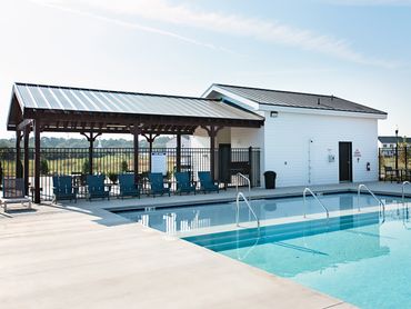 Outdoor swimming pool with shaded seating area and clear blue water.