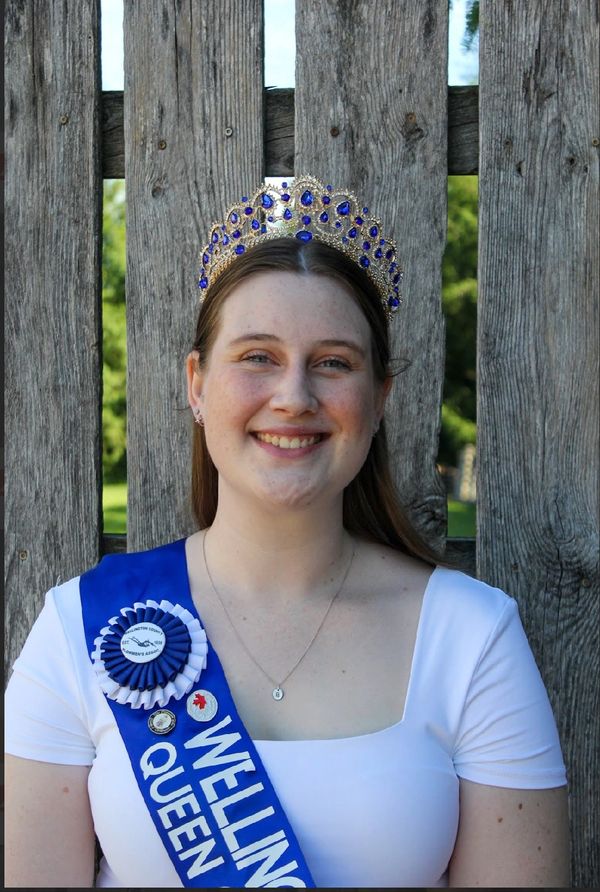 Young woman wearing a crown and sash smiling.
