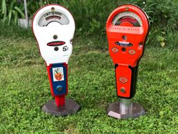 Two Rockwell parking meters one white and red and the other is all red.