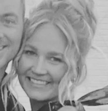 Black and white photo of a smiling woman with styled hair.