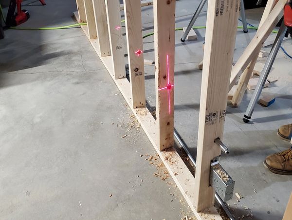 Laser level lines on wooden studs during wall framing construction.