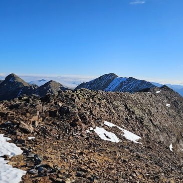 Rocky mountain peaks with patches of snow under a clear blue sky.