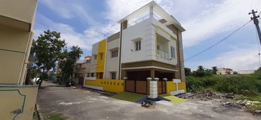 Modern two-story house with yellow and white exterior on a quiet street.