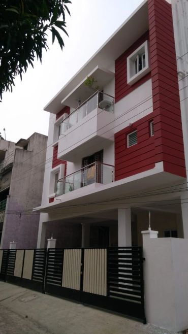 Modern three-story house with white and red exterior and glass balconies.