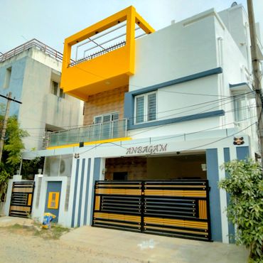 Modern house with yellow, white, and blue exterior and a black gate.