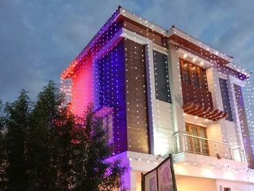Modern three-story house decorated with colorful string lights at dusk.