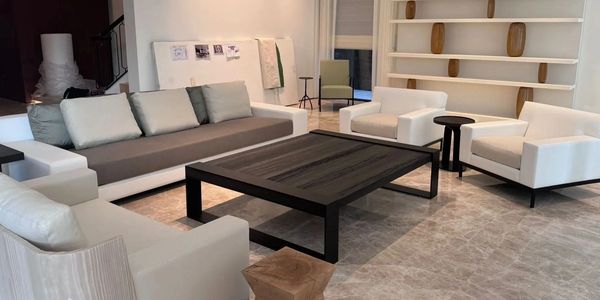 Modern living room with white armchairs and a large gray sofa around a black coffee table.