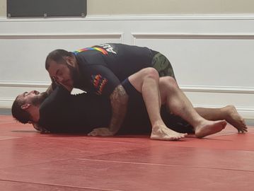 Two men grappling on a mat during training.