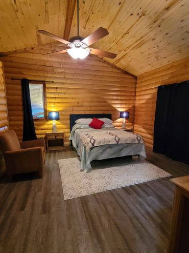 Cozy log cabin bedroom with warm lighting and simple decor.