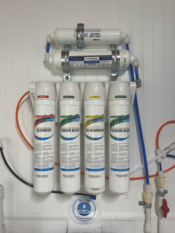 A water filtration system with sediment, carbon block, and RO membrane filters installed on a wall.