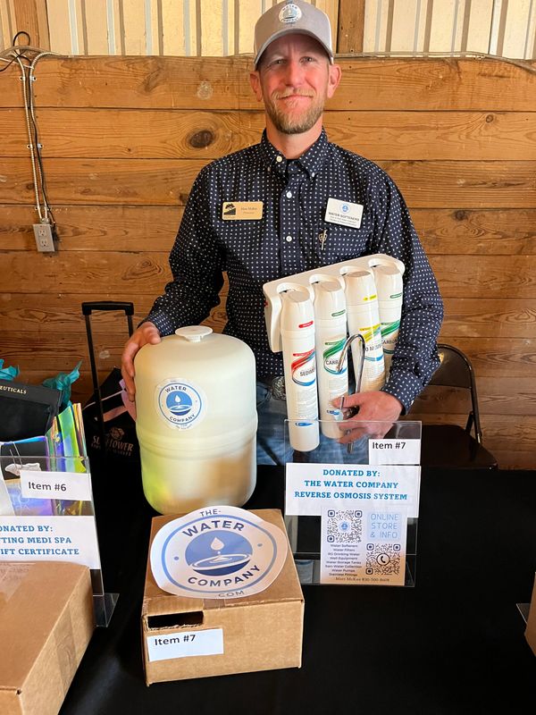 Man presenting a water filtration system donated by The Water Company.