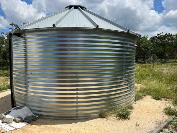 A large metal water storage tank outdoors under a partly cloudy sky.