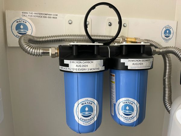 Dual blue water filters labeled for carbon and sediment filtration with replacement date August 2024.