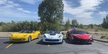 Three colorful Corvettes parked side by side under a bright sky.