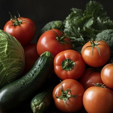 A rustic arrangement of fresh vegetables including tomatoes, cabbage, cucumbers, broccoli, and bananas.