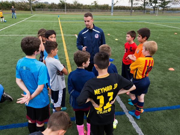 Soccer coach talking to a group of players in a circle