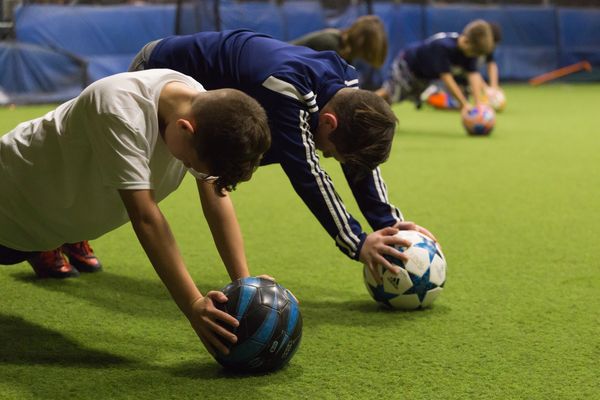 Youth soccer players doing an ab workout with their soccer ball