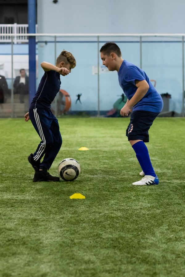 One youth soccer player dribbling at another