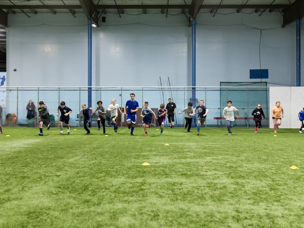 Youth soccer players running in a line on an indoor soccer field