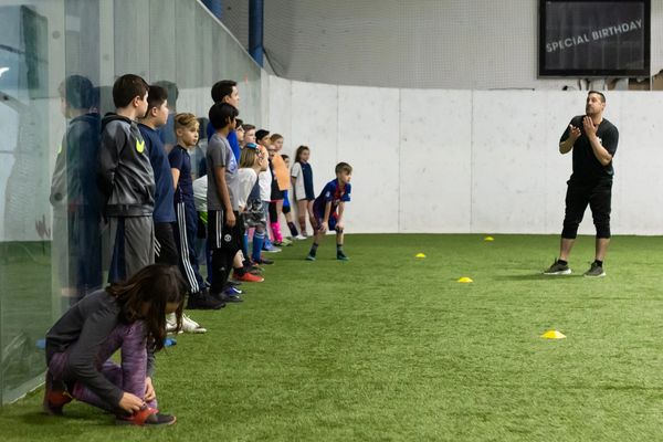 Youth soccer coach talking to players standing against a wall
