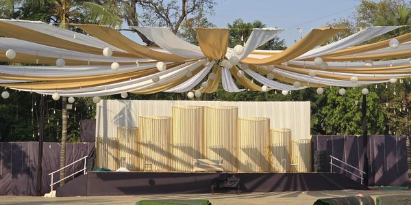 Elegant outdoor stage setup with draped fabric and lanterns under a clear sky.