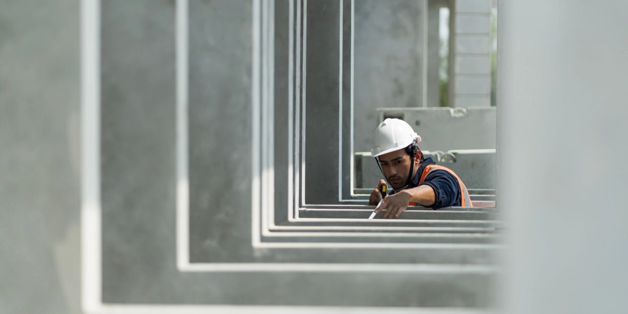 Construction worker measuring within a concrete frame structure.