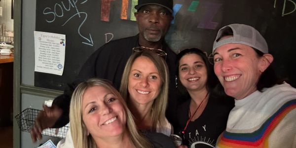 Group of five friends smiling and posing for a selfie indoors.
