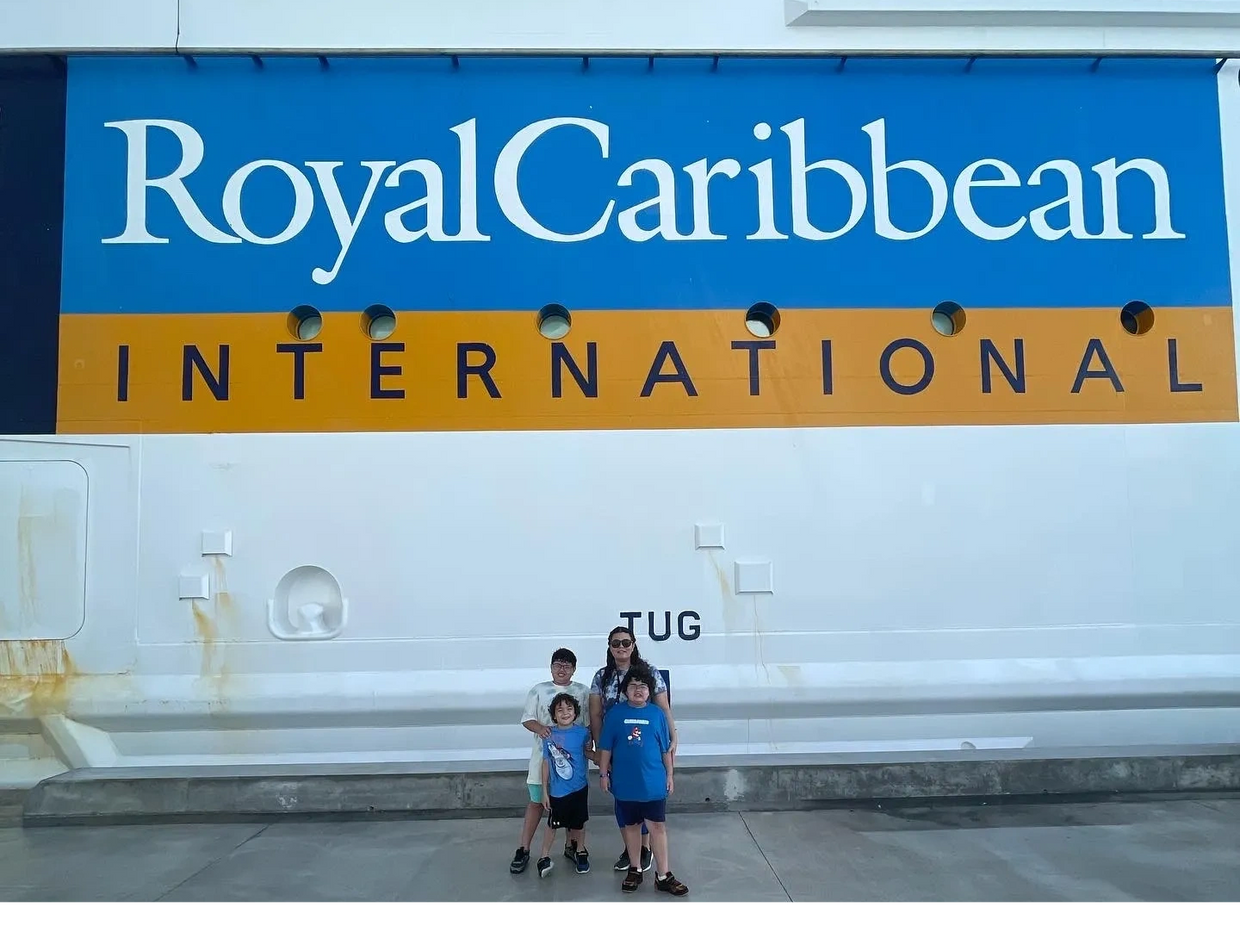 A family poses in front of a Royal Caribbean International cruise ship.