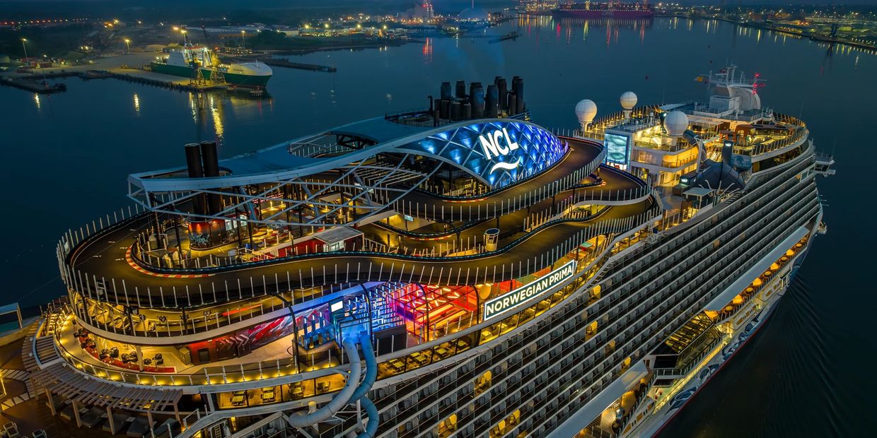 The Norwegian Prima cruise ship illuminated at night in port.
