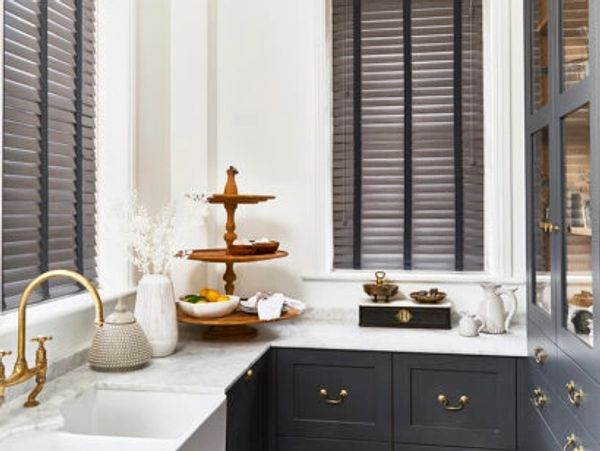 wood slat blind in grey with with black tapes in a kitchen. dark grey units white countertop