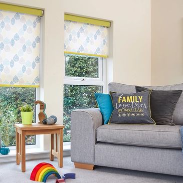 leaf print roller blind in soft yellow and blue on a white background with a yellow senses cassette