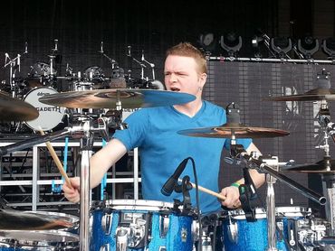 A drummer intensely playing a blue drum set on stage.