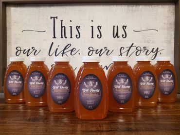 Bottles of Wild Flowers Raw Honey displayed in front of a framed inspirational quote.