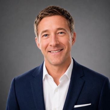 Smiling man in a navy suit and white shirt.