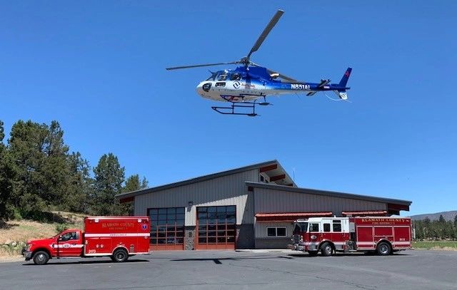 Station 5 with an ambulance and engine parked in front with a helicopter hovering over them.