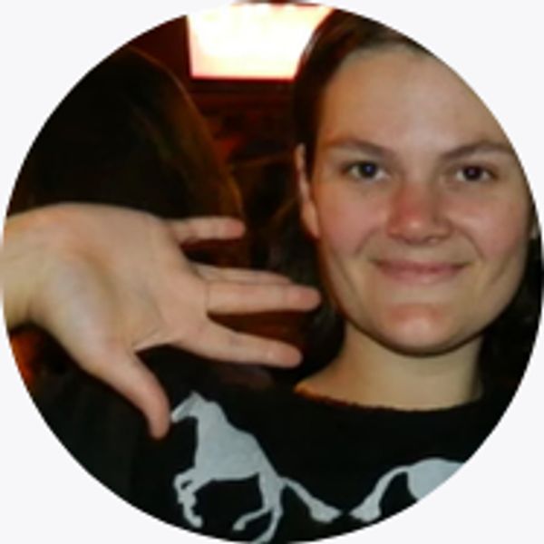 Young woman smiling with hand raised.