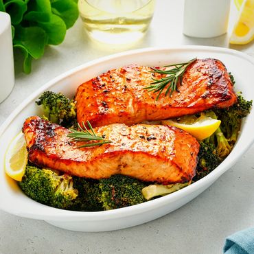 Grilled salmon fillets on a bed of roasted broccoli garnished with lemon and rosemary.
