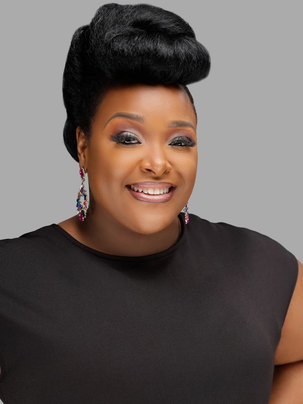 Smiling woman with elegant hairstyle and colorful earrings.