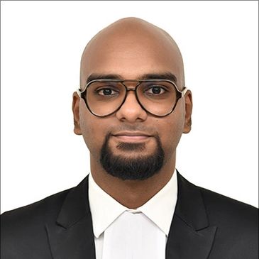 Professional headshot of a bald man wearing glasses and a black suit.