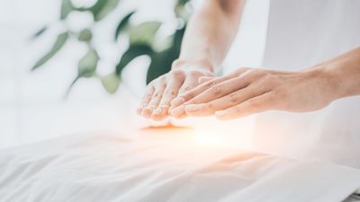 Healing hands channeling light energy to a client during a reiki session