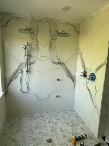 Modern dual shower heads in a sleek marble-tiled bathroom.