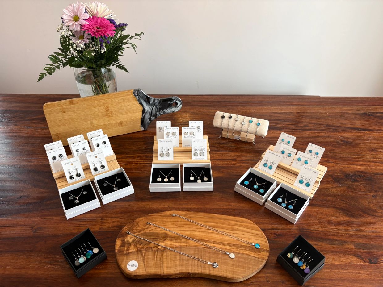 Elegant jewelry sets displayed on wooden boards with a flower vase in the background.