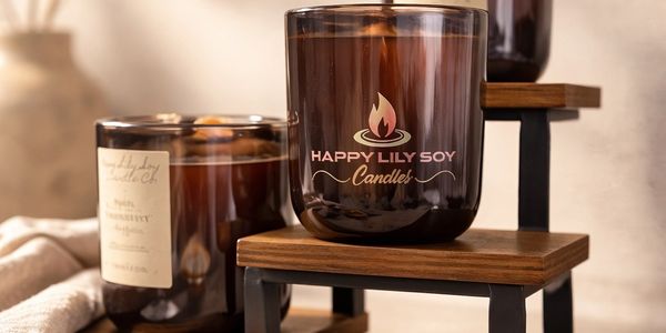 Elegant soy candles in amber glass jars displayed on wooden shelves.