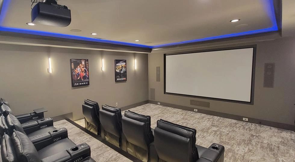 Modern home theater with recliner seats and large screen.