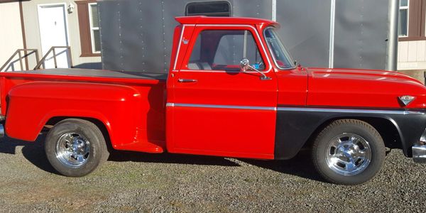 Classic red and black vintage pickup truck parked outdoors.