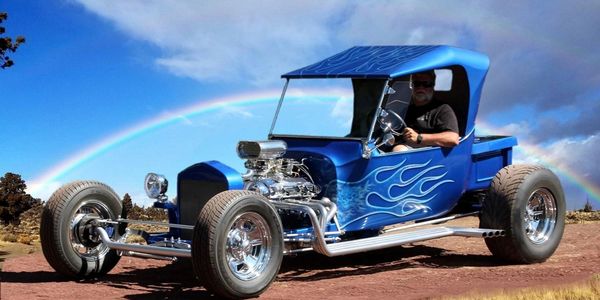 Custom blue hot rod car with flame decals and a rainbow in the background.