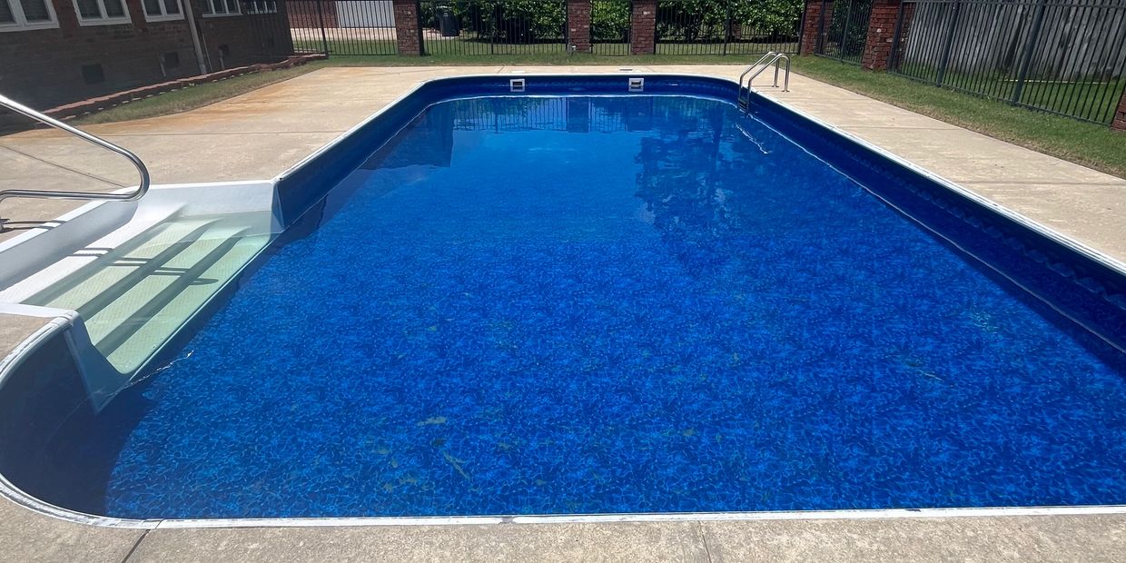 A clear blue swimming pool with steps on a sunny day.