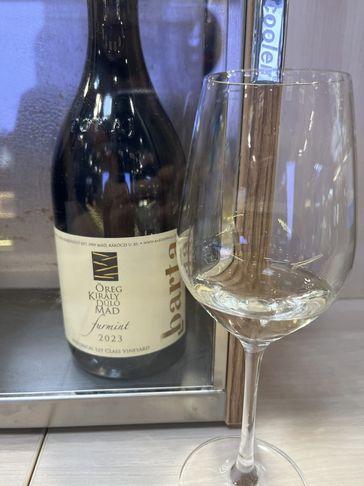 A bottle of 2023 Juhfint wine and a glass with white wine.