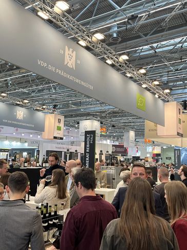 Crowded wine tasting event with many attendees sampling wines.