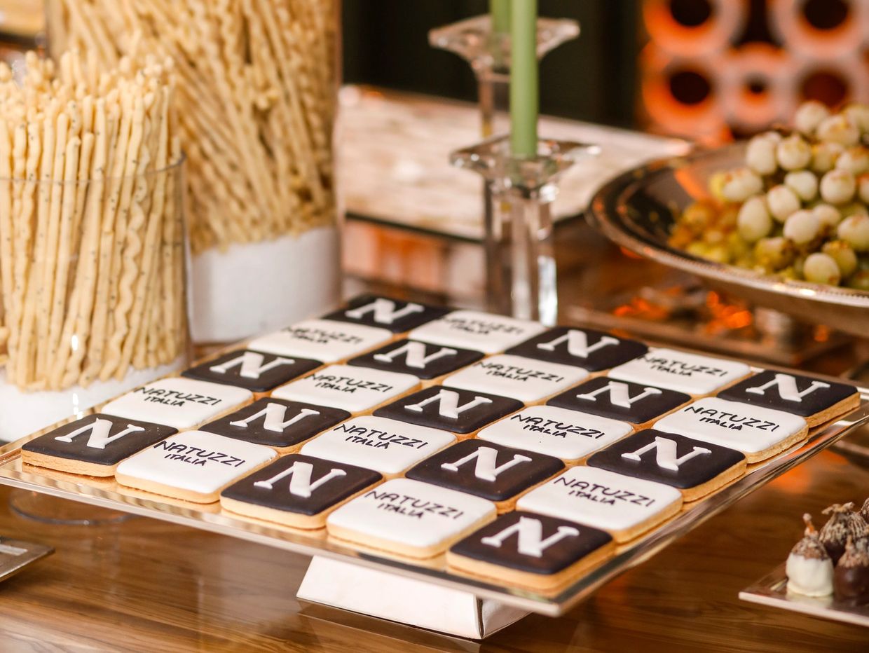 Square cookies with black and white icing displaying 'N' and 'Natuzzi Italia'.